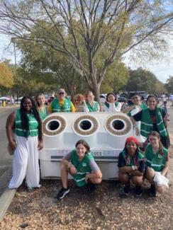 a group of G4 volunteers around one of the G4 waste bins. They're all wearing green vests.