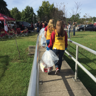 Students Walking with Recycling Bags at Football Tailgates