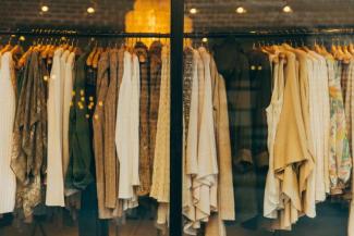 Clothing rack with tan, beige, and white clothes handing up.